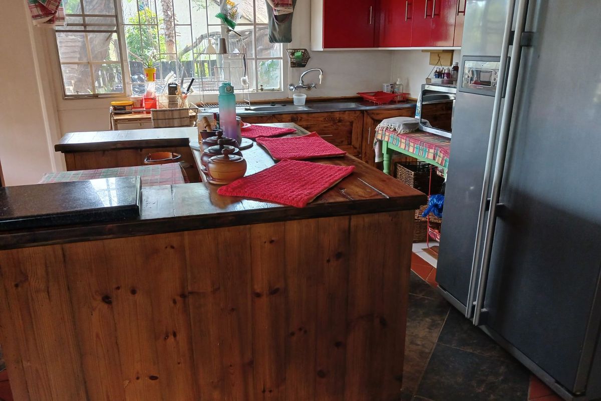 A rustic kitchen featuring wooden cabinetry, a central island, and red upper cabinets, offering a functional workspace with natural light from the window.