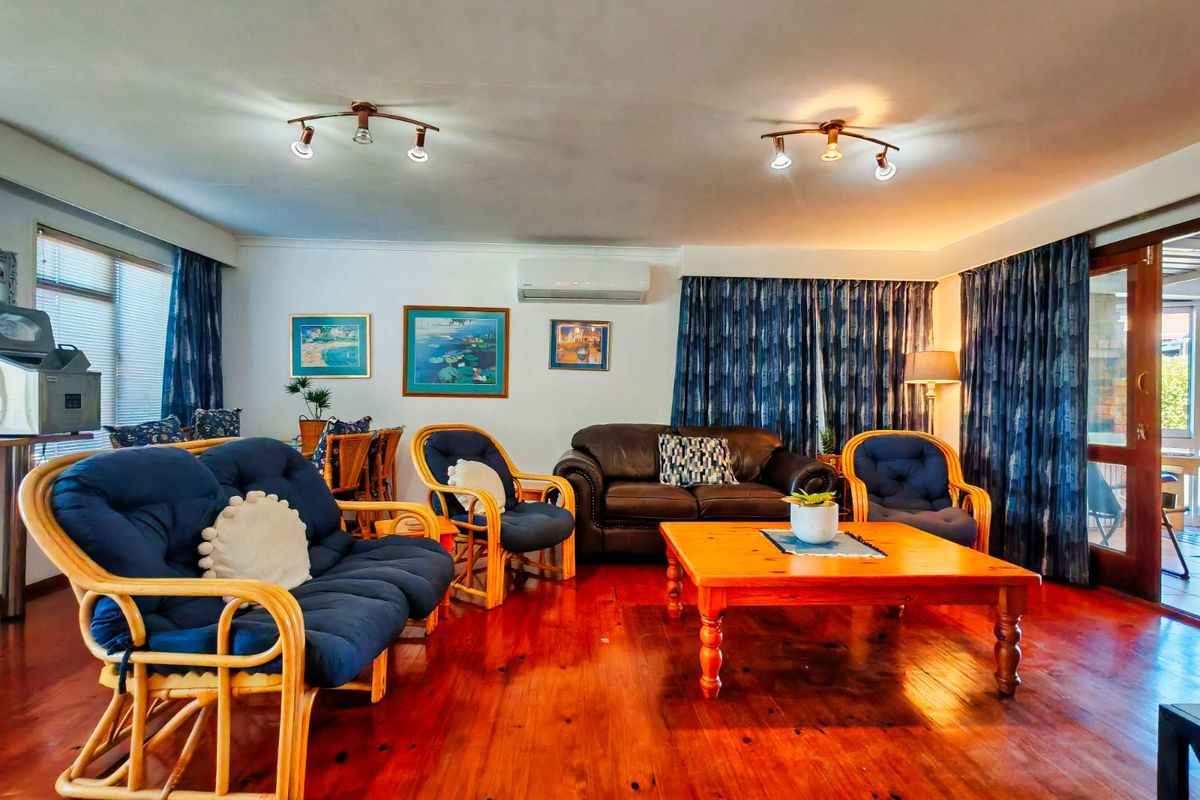 Spacious living room featuring polished hardwood flooring, split-system air conditioning, and direct access to an outdoor area through a timber-framed glass door.