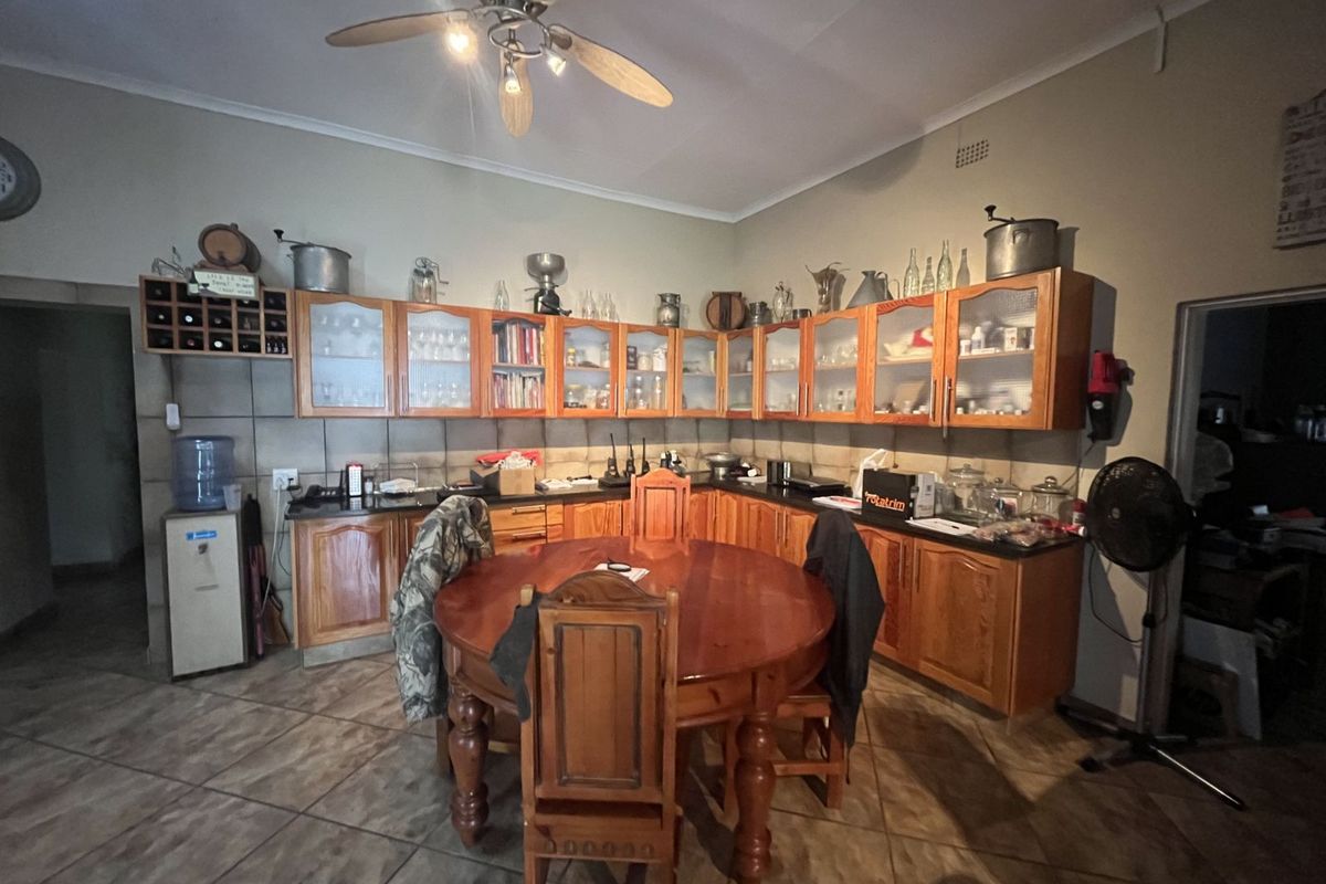 A functional kitchen featuring wooden cabinetry, tiled flooring, and a central dining area, offering a traditional farmhouse aesthetic with ample storage space.