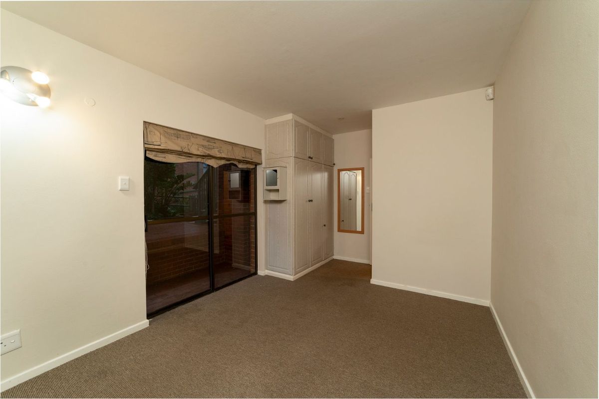 A bedroom featuring built-in cabinetry, carpeted flooring, and a sliding glass door providing access to an outdoor area.