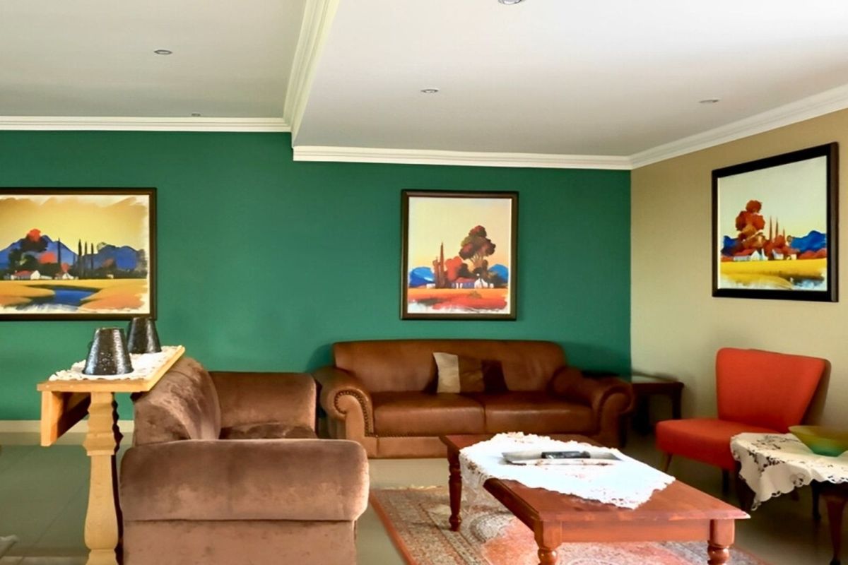 A spacious living room featuring recessed ceiling lighting, decorative crown molding, and tiled flooring, providing a comfortable area for relaxation.
