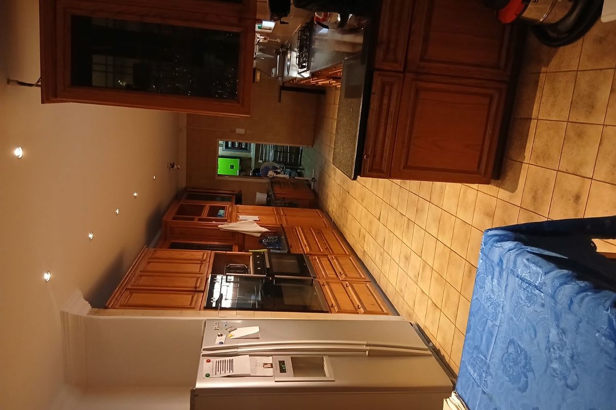 A spacious kitchen featuring extensive wooden cabinetry, granite countertops, built-in appliances, and tiled flooring, offering a functional layout with ample storage.