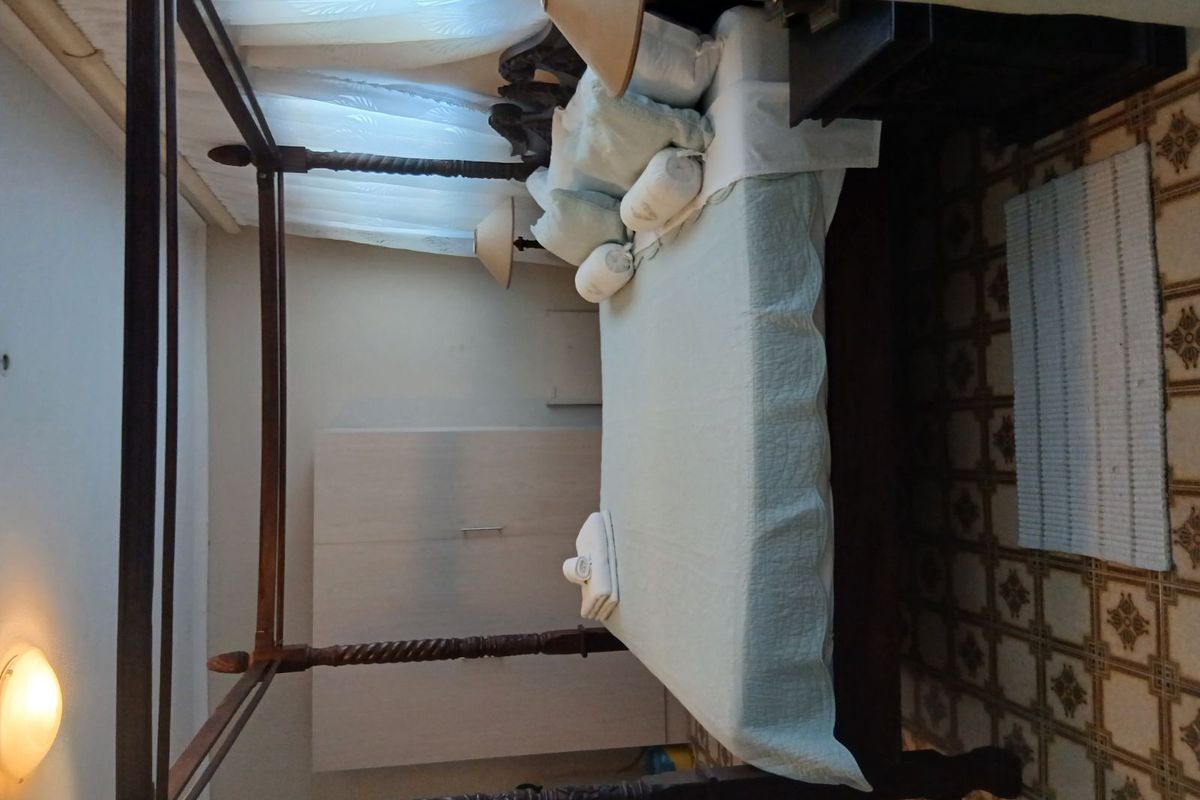 A bedroom featuring a built-in wardrobe and dated floor tiling, offering a functional space with potential for modern updates.