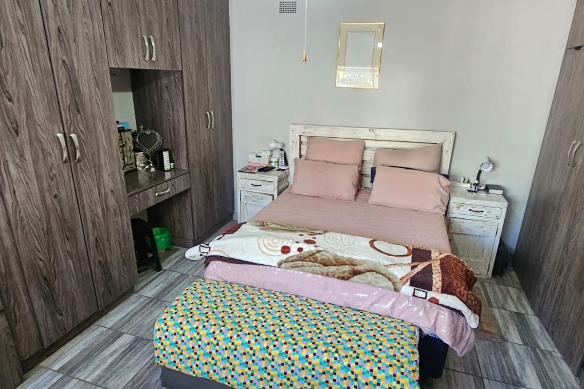 A well-maintained bedroom featuring extensive built-in wooden cabinetry with an integrated vanity area and modern tiled flooring.
