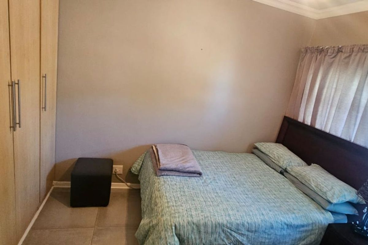 A bedroom featuring built-in wooden wardrobes and tiled flooring, providing functional storage and a neutral living space.
