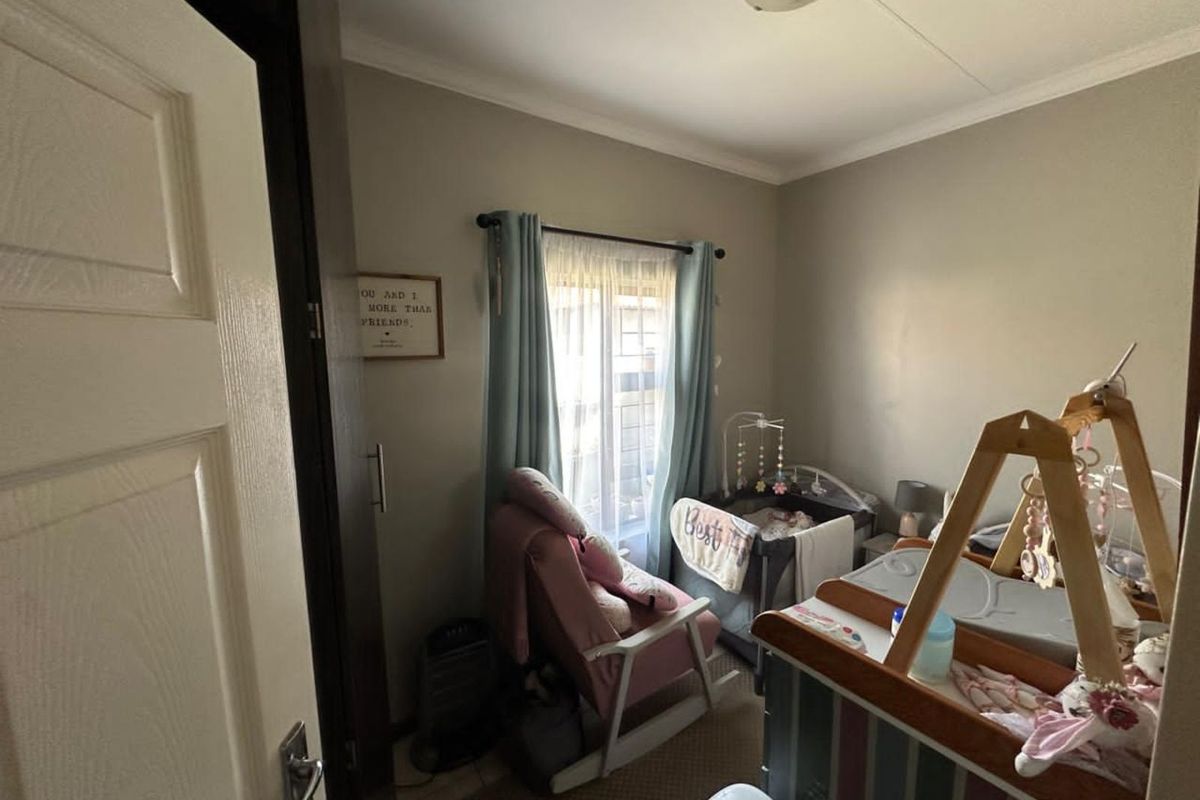 A standard bedroom featuring neutral wall tones, tiled flooring, and a window with curtain fixtures, suitable for a nursery or guest room.