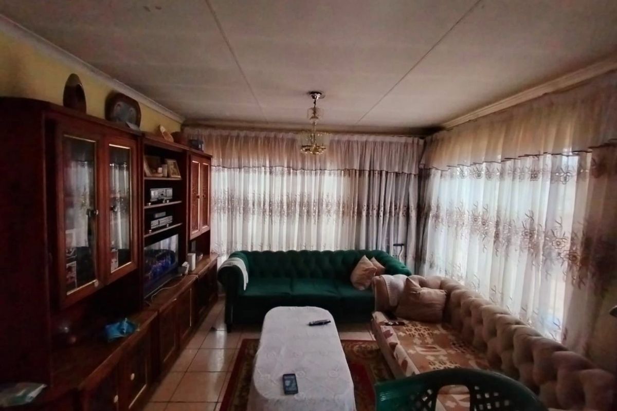A living room featuring tiled flooring and a ceiling with visible water staining, requiring cosmetic updates to modernize the space.