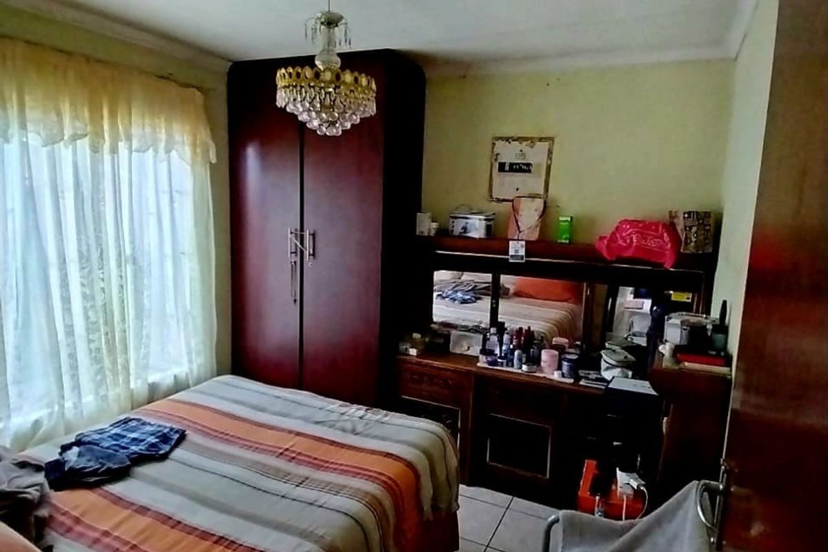 A bedroom featuring tiled flooring, a built-in wardrobe, and a central chandelier light fixture.