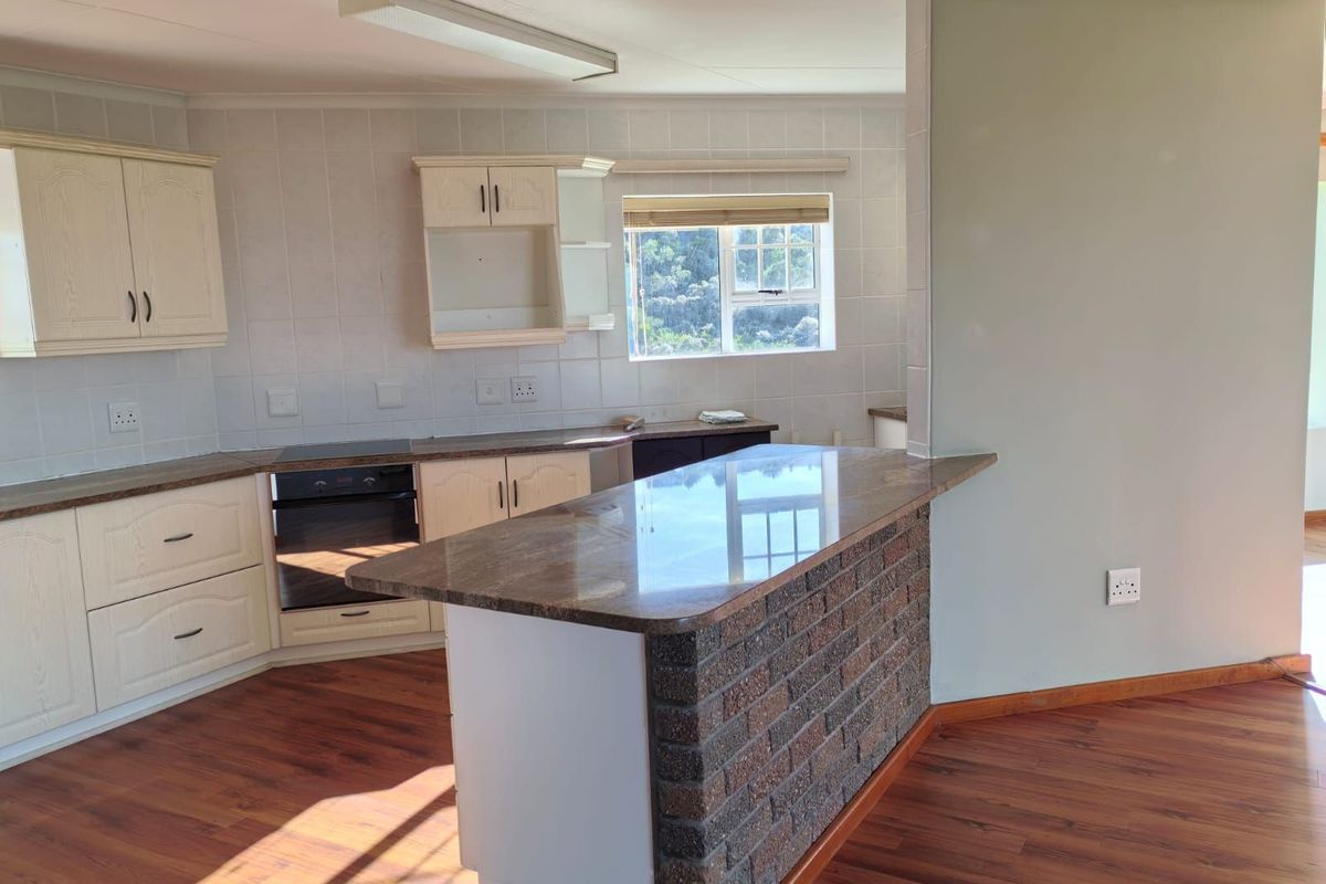 A functional kitchen featuring a breakfast bar with a brick base, laminate countertops, built-in oven, and hob, finished with wood-look flooring.