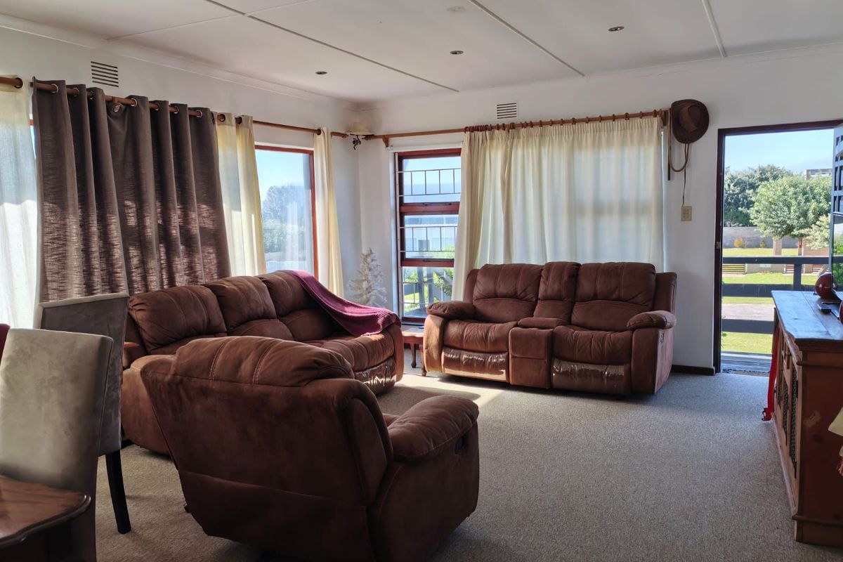 A spacious living room featuring large windows, carpeted flooring, and direct access to the outdoor area.