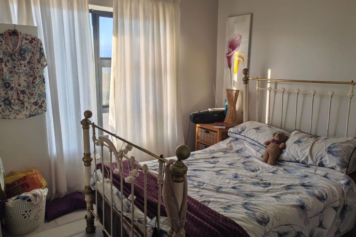 A cozy bedroom featuring tiled flooring, crown molding, and large windows with natural light, providing a comfortable and functional living space.