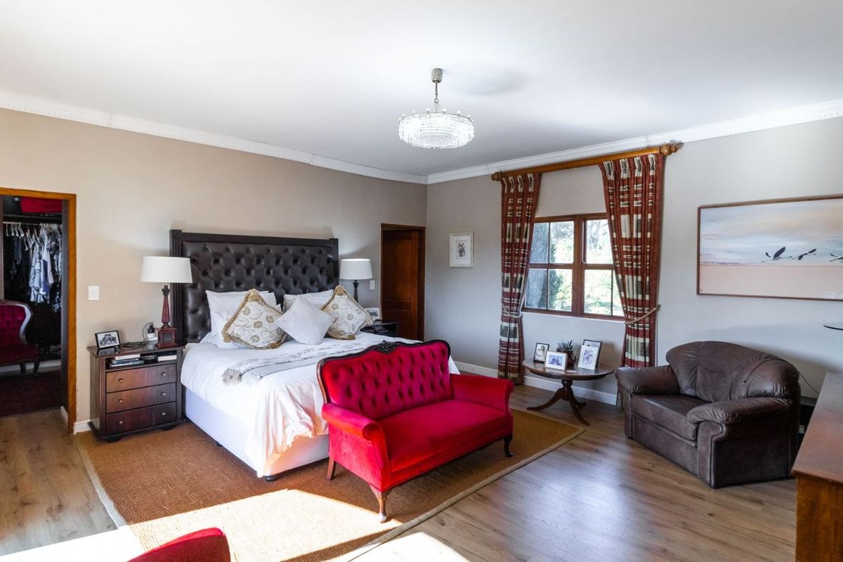 Spacious bedroom featuring wood-look flooring, crown molding, and an integrated walk-in closet with built-in shelving.