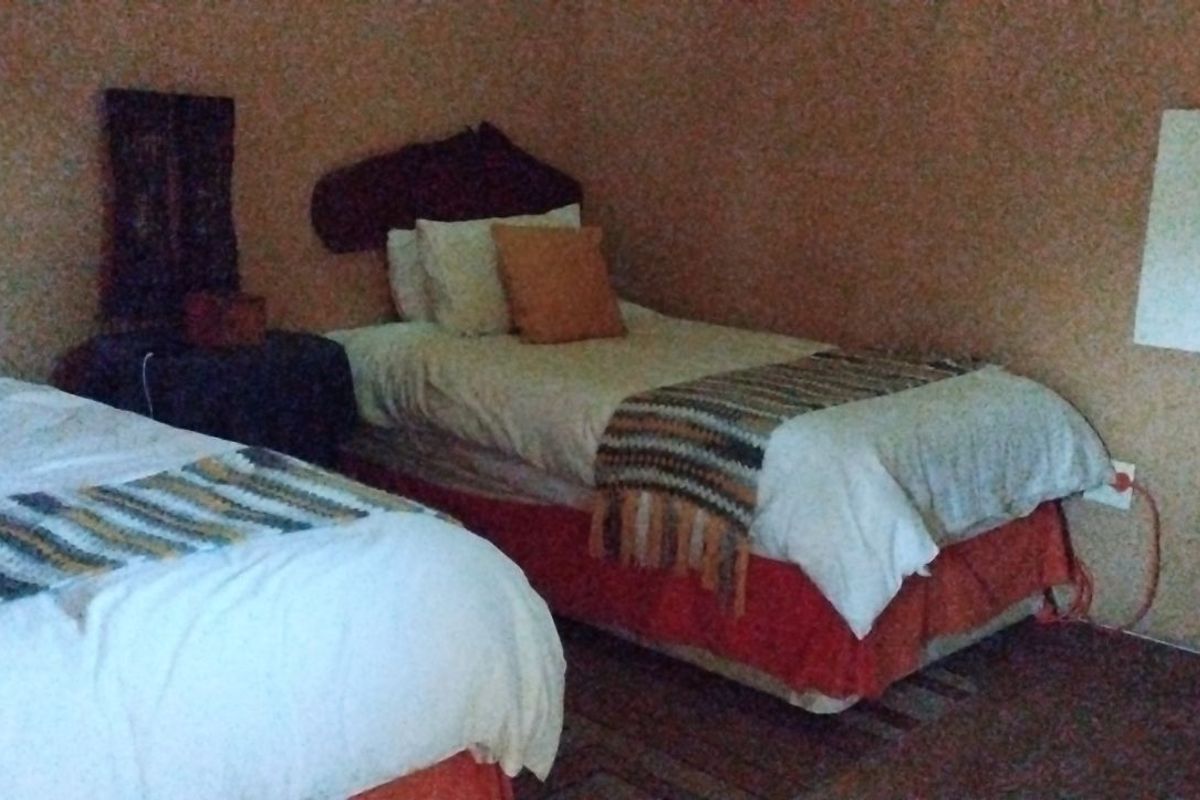 A rustic bedroom featuring twin beds with textured wall finishes and a wall-mounted heating panel.