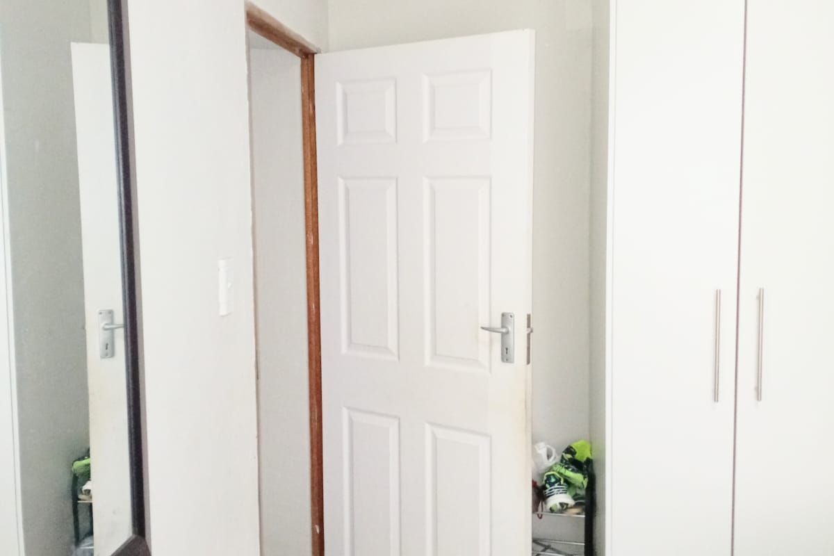 A bedroom interior featuring built-in white cabinetry and a standard panel door, providing functional storage and access to the adjoining space.