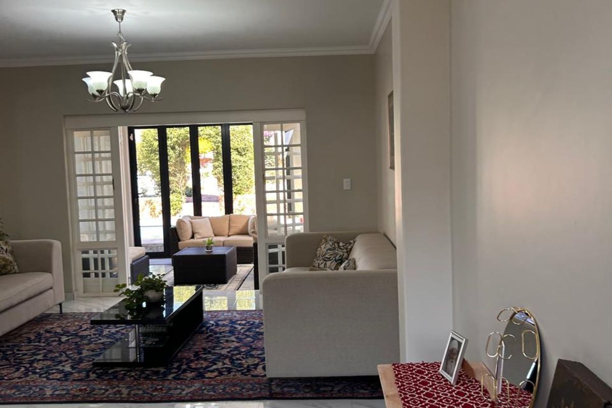 Spacious living area featuring polished marble-look tile flooring, crown molding, and large glass sliding doors opening to an outdoor patio space.