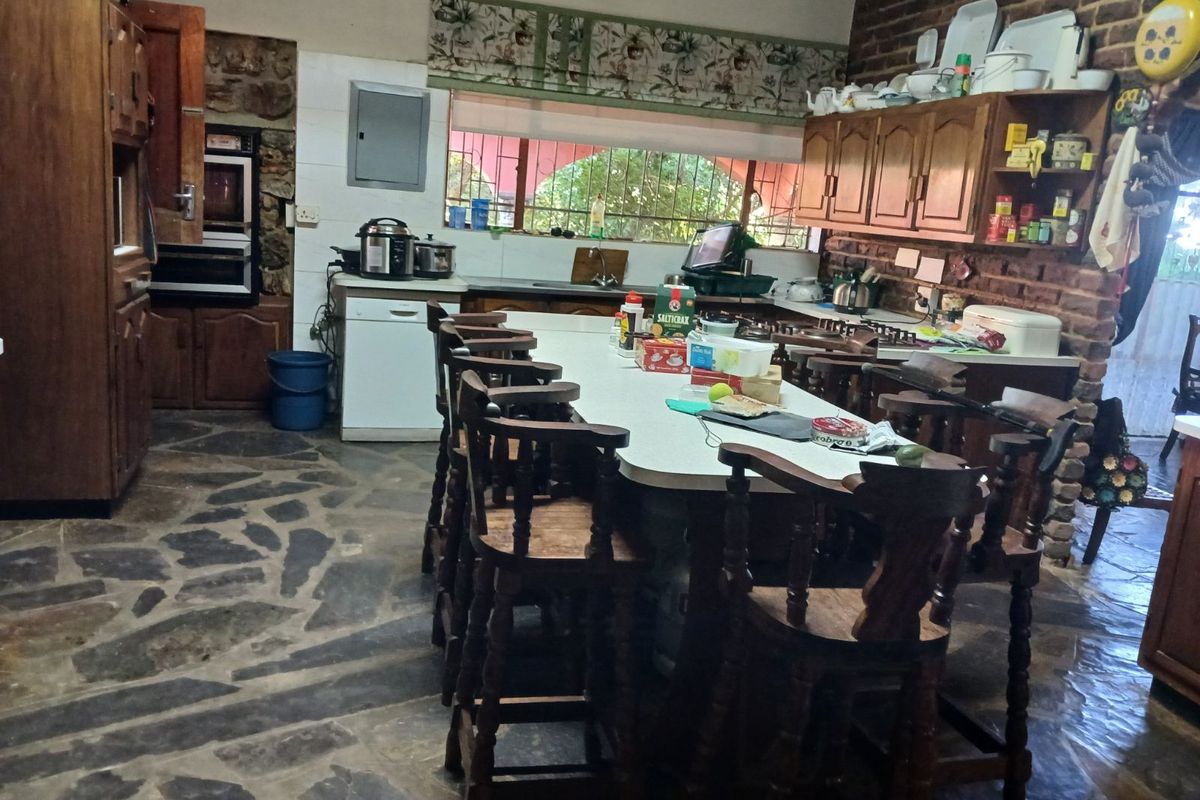 Rustic farmhouse kitchen featuring exposed brick walls, stone flooring, a large central island, and traditional wooden cabinetry.