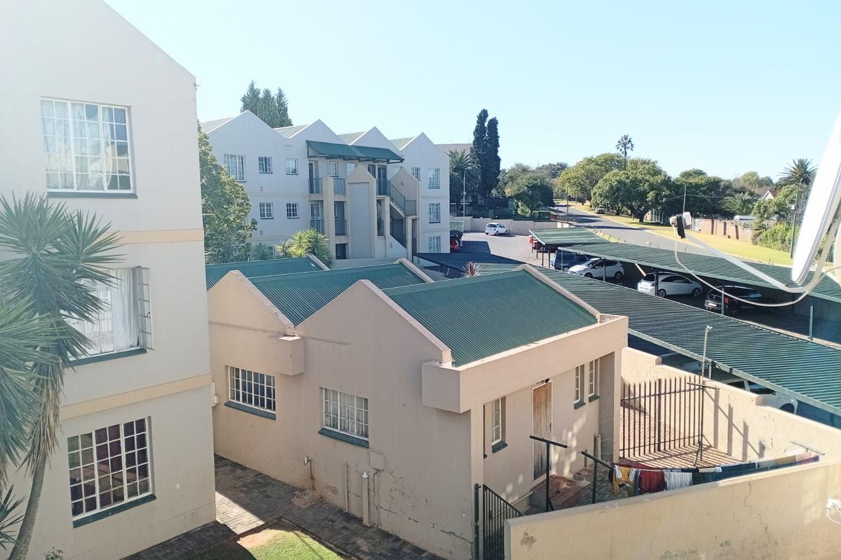 An elevated view of the apartment complex grounds, featuring residential buildings, covered parking bays, and paved walkways.