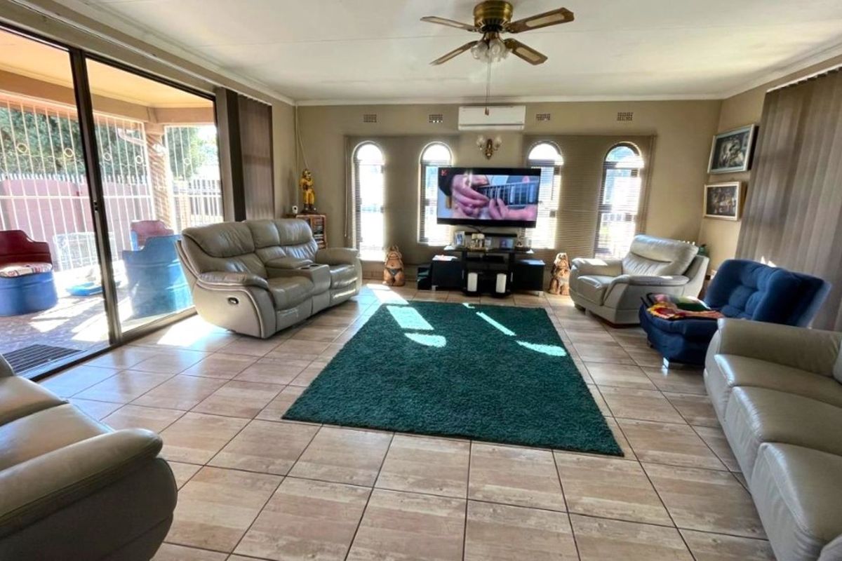 Spacious living room featuring ceramic floor tiles, arched windows, and a wall-mounted air conditioning unit, with direct access to an outdoor patio area.