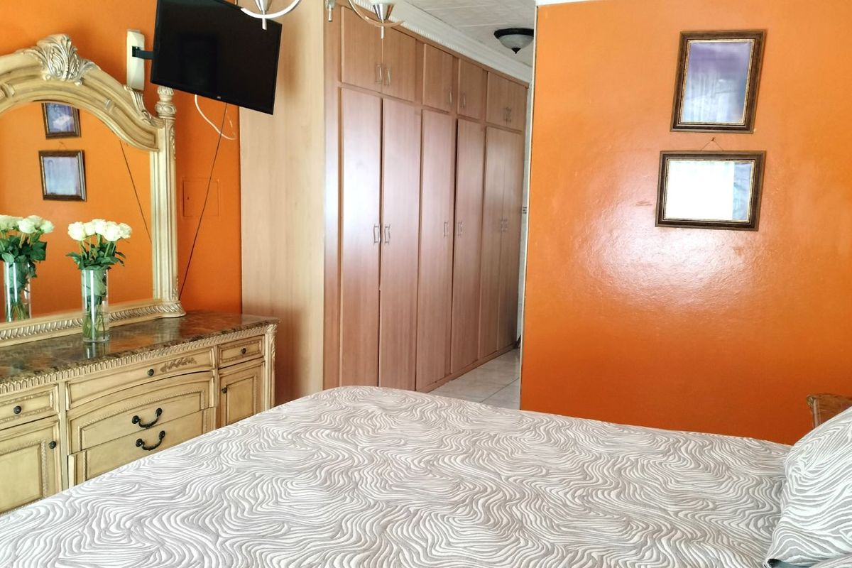 A bedroom featuring built-in wooden wardrobes and a vanity area with a large mirror.