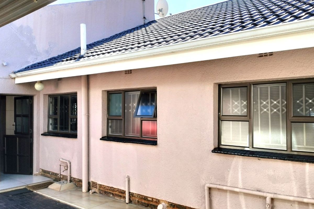 Rear exterior view of the house featuring tiled flooring, aluminium window frames with security bars, and a pitched tiled roof.