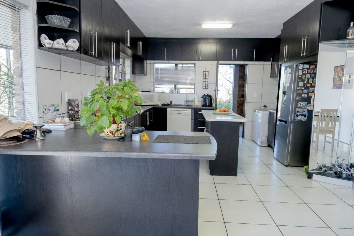 A functional kitchen featuring dark cabinetry, tiled flooring, and a central island, providing ample storage and workspace for daily meal preparation.