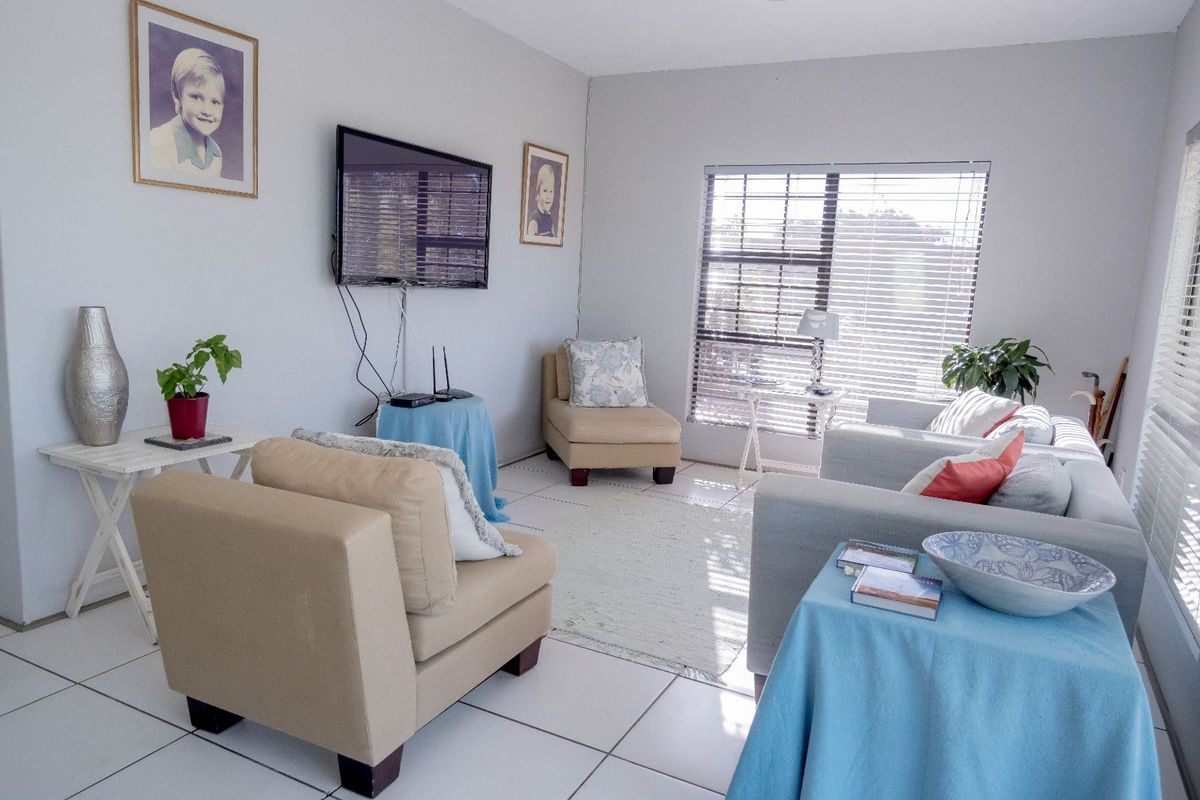 A bright living room featuring tiled flooring and large windows with fitted blinds, providing a comfortable and functional space.