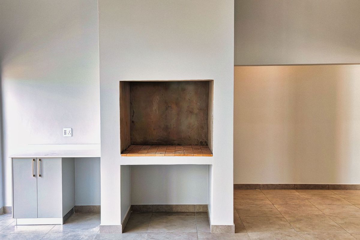 A clean, open-plan living area featuring a built-in indoor fireplace and adjacent cabinetry with a stone countertop.