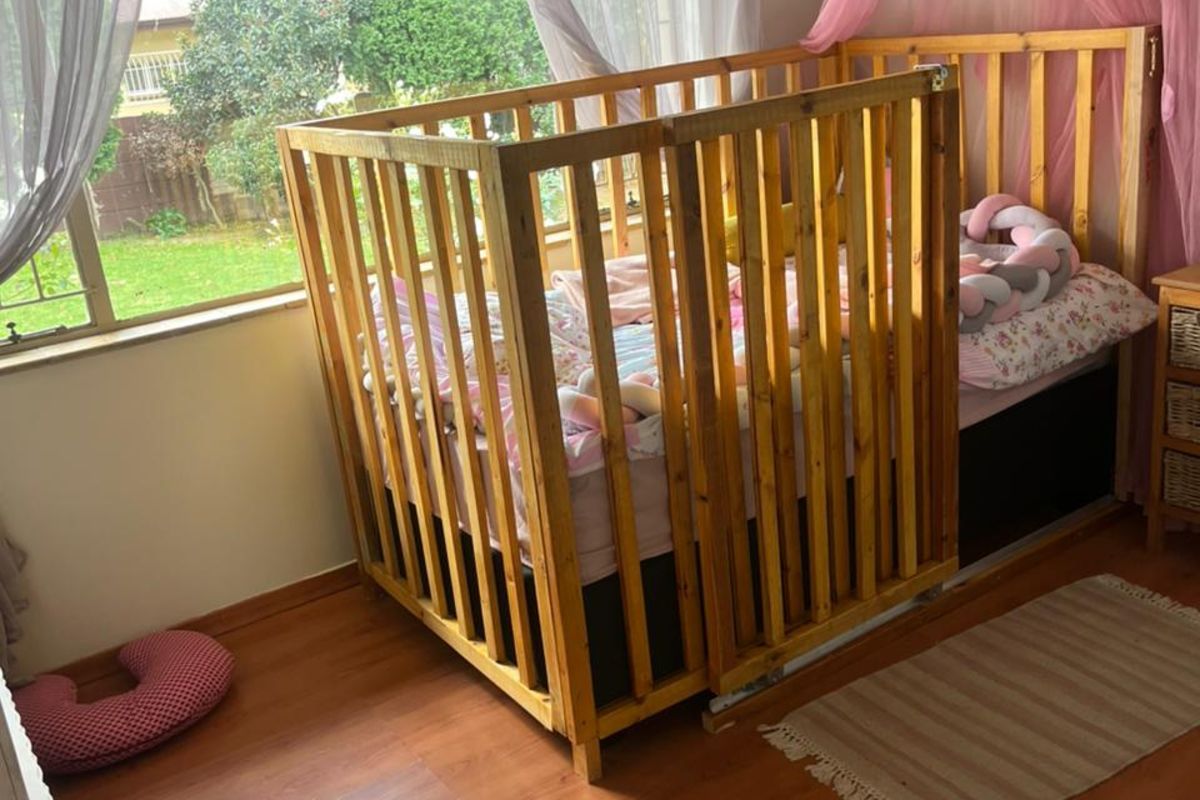 A bedroom featuring laminate flooring and a large window with natural light, providing a view of the garden area.