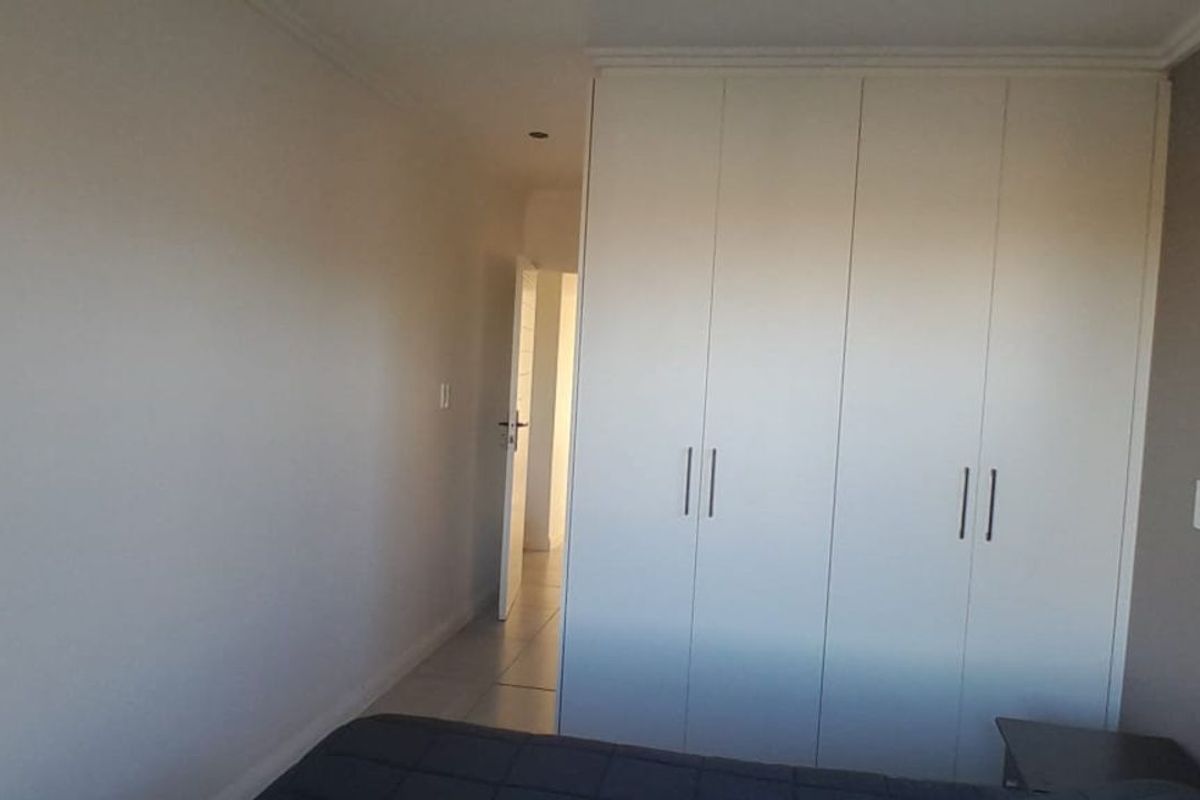 A bedroom featuring built-in white cabinetry and tiled flooring, providing ample storage space and a clean, neutral aesthetic.