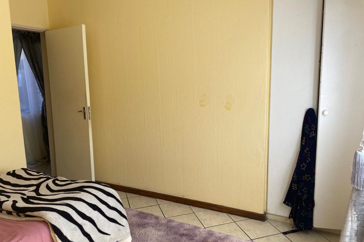 A bedroom featuring tiled flooring, a built-in wardrobe, and a doorway leading to an adjacent space.