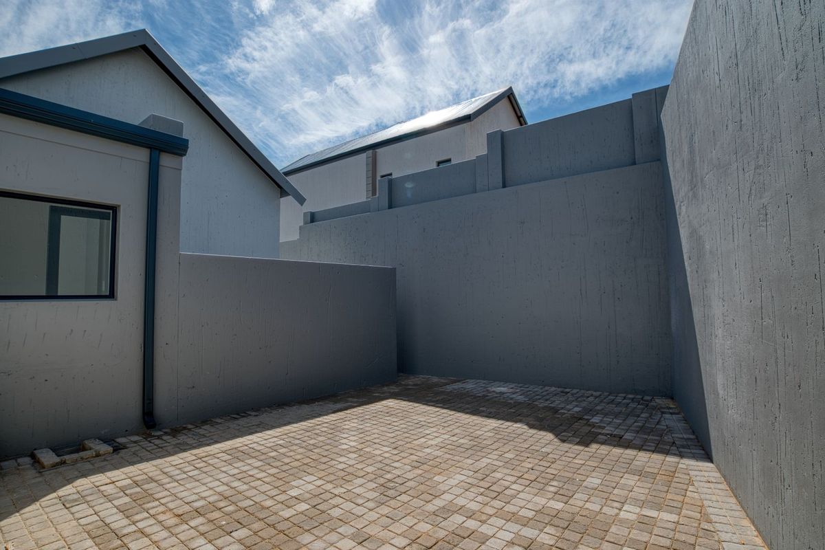 A private, paved courtyard area enclosed by high boundary walls, offering a secure and low-maintenance outdoor space.