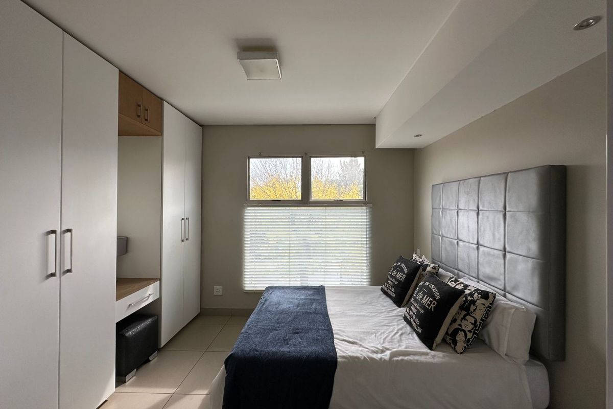 A well-maintained bedroom featuring built-in white cabinetry with an integrated vanity and tiled flooring.