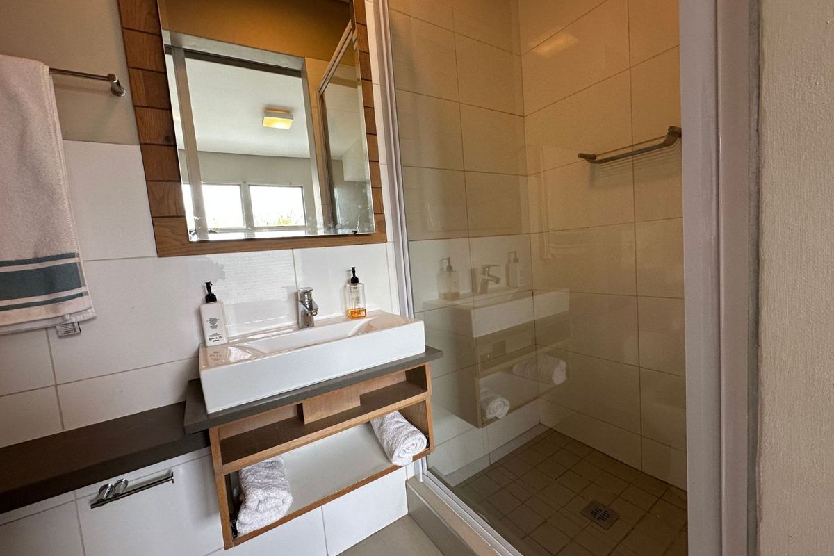Modern bathroom featuring a floating vanity with a vessel sink, a framed mirror, and a glass-enclosed walk-in shower with tiled walls.