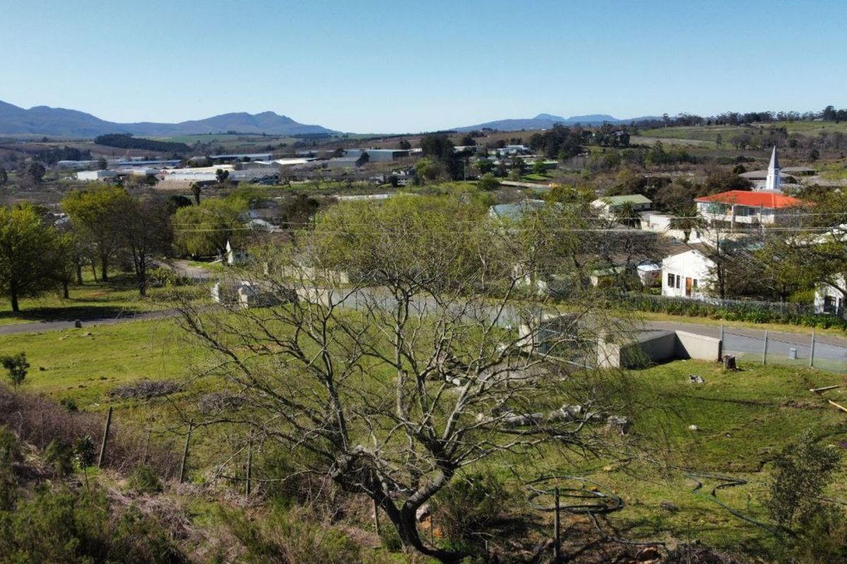 An elevated aerial view overlooking the surrounding neighbourhood, local infrastructure, and distant mountain landscape.