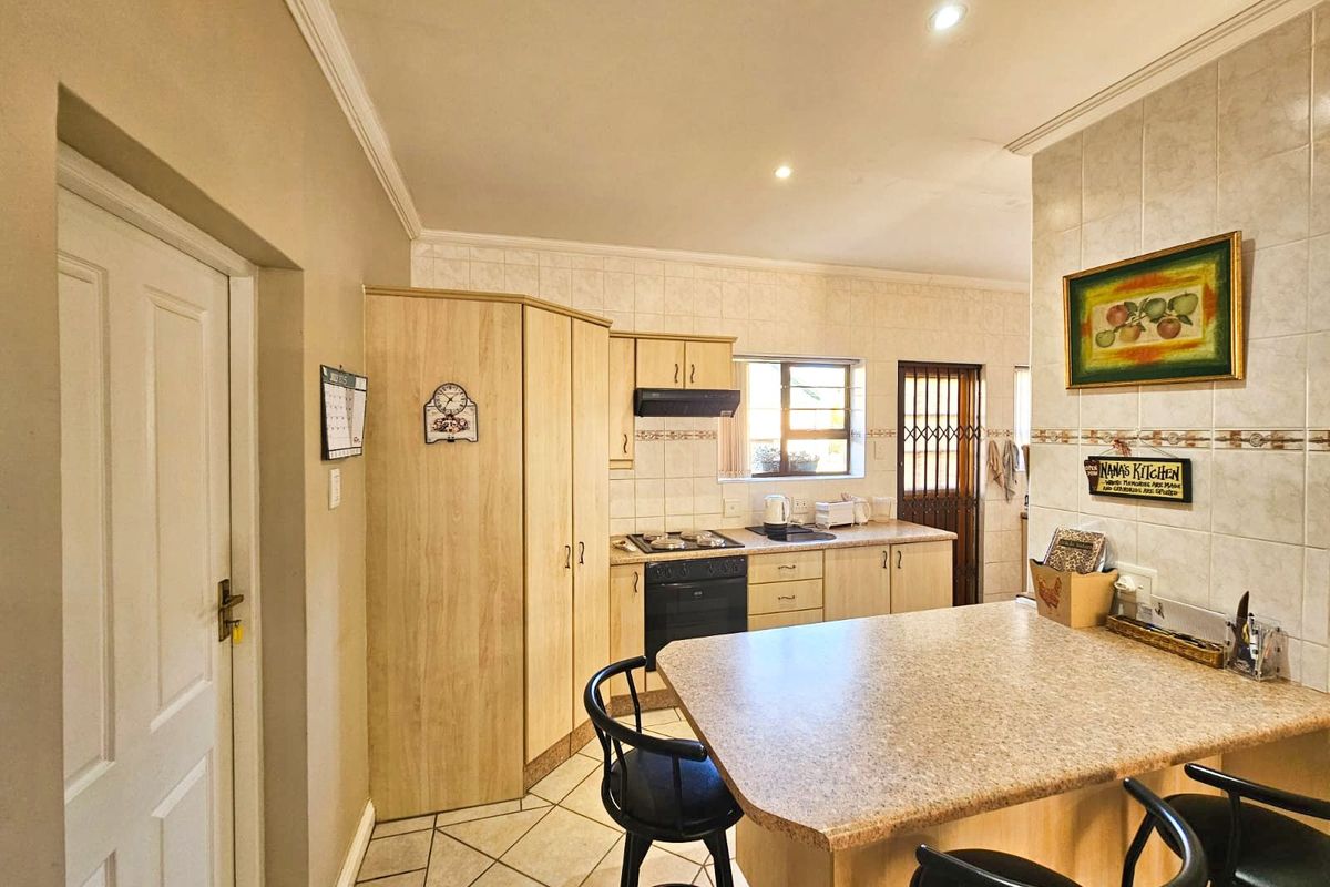 Functional kitchen featuring light wood cabinetry, tiled splashbacks, a breakfast bar, and built-in stove with extractor fan.
