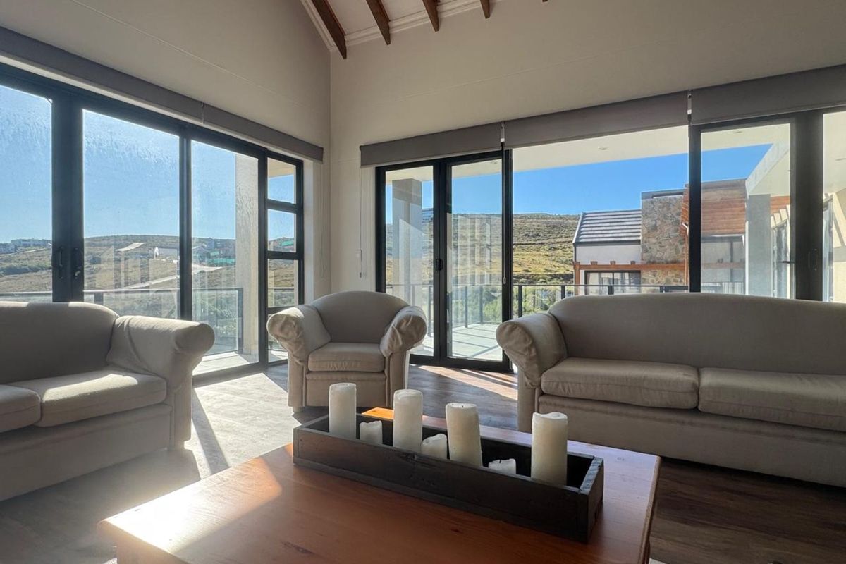 Spacious living room featuring high vaulted ceilings with exposed timber beams and large sliding glass doors opening to an outdoor balcony.
