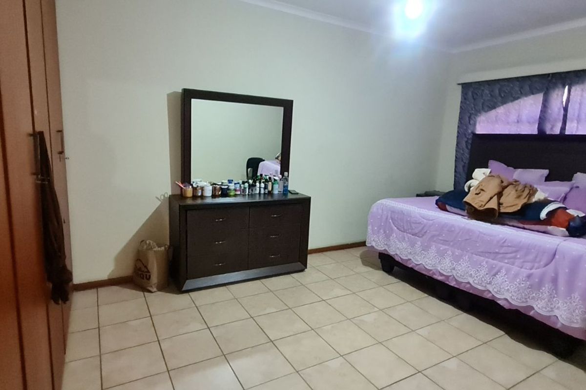 A bedroom featuring built-in wooden cupboards and tiled flooring, providing a functional and spacious layout.