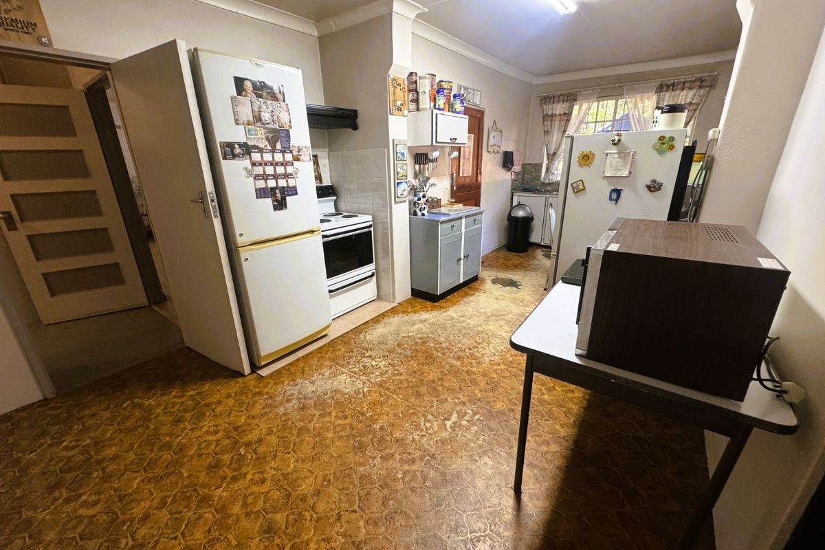 A functional kitchen space featuring built-in cabinetry, a stove with extractor fan, and tiled flooring, offering potential for modernization and cosmetic updates.