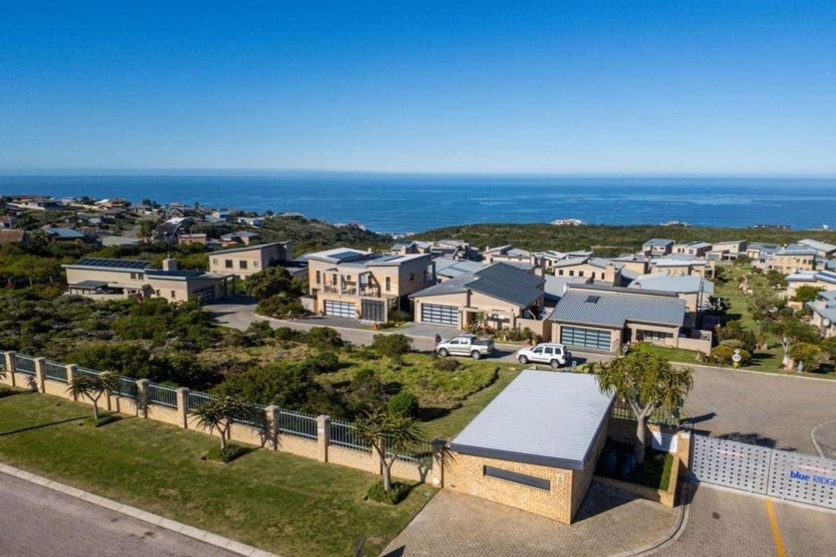 Aerial view of a residential estate featuring modern homes, paved driveways, and coastal views.