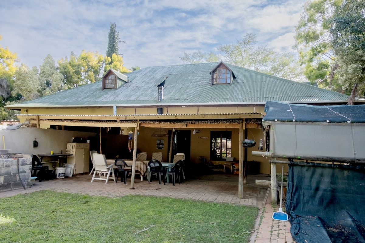 Rear view of a farm-style dwelling featuring a large covered patio area with a corrugated metal roof and dormer windows.