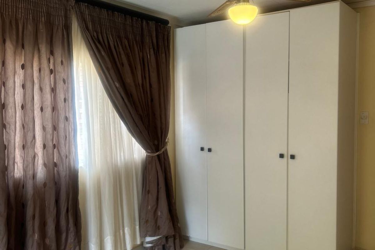 A bedroom featuring tiled flooring, a built-in wardrobe, and a ceiling fan.