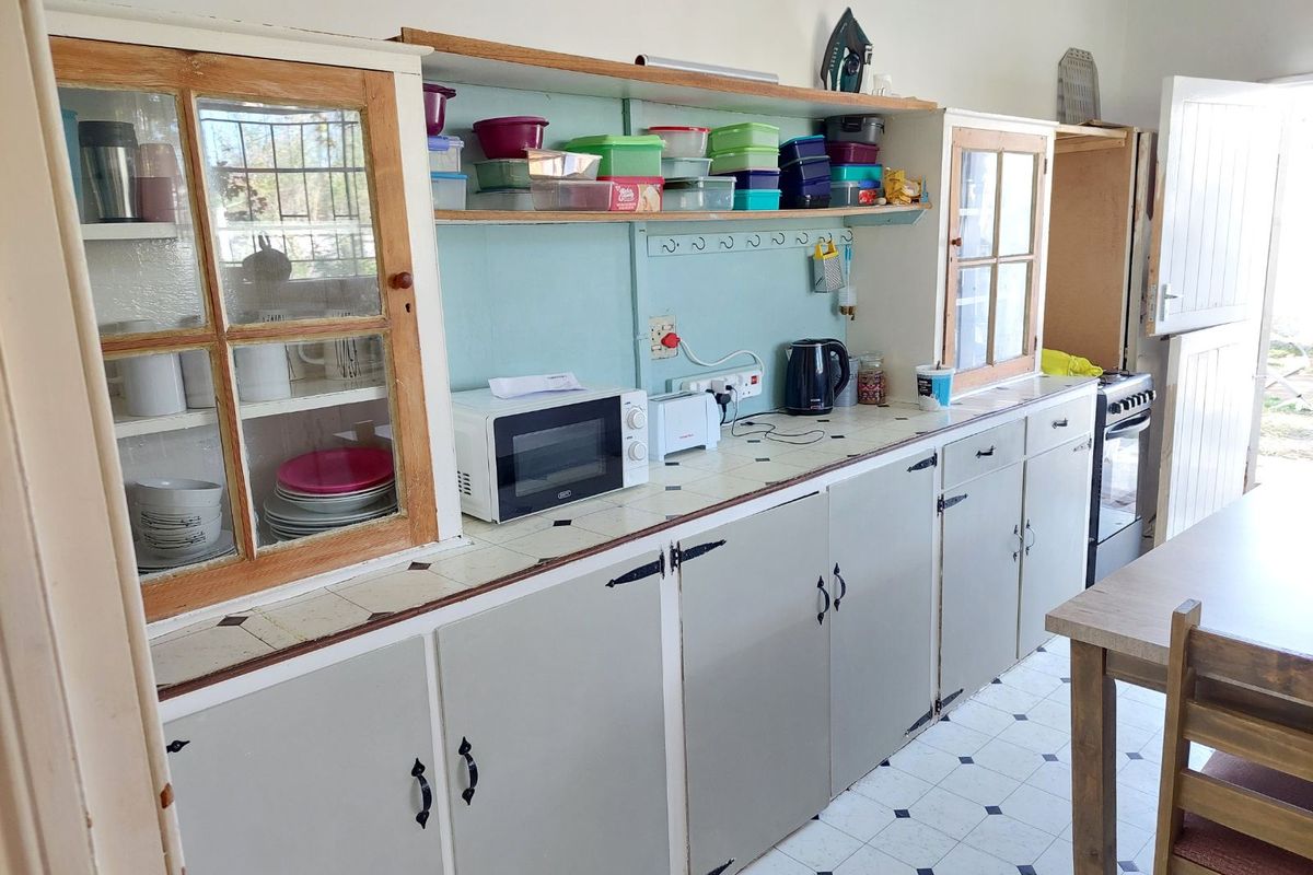 A dated kitchen featuring built-in cabinetry with glass-front display units, tiled countertops, and a classic checkerboard floor pattern.