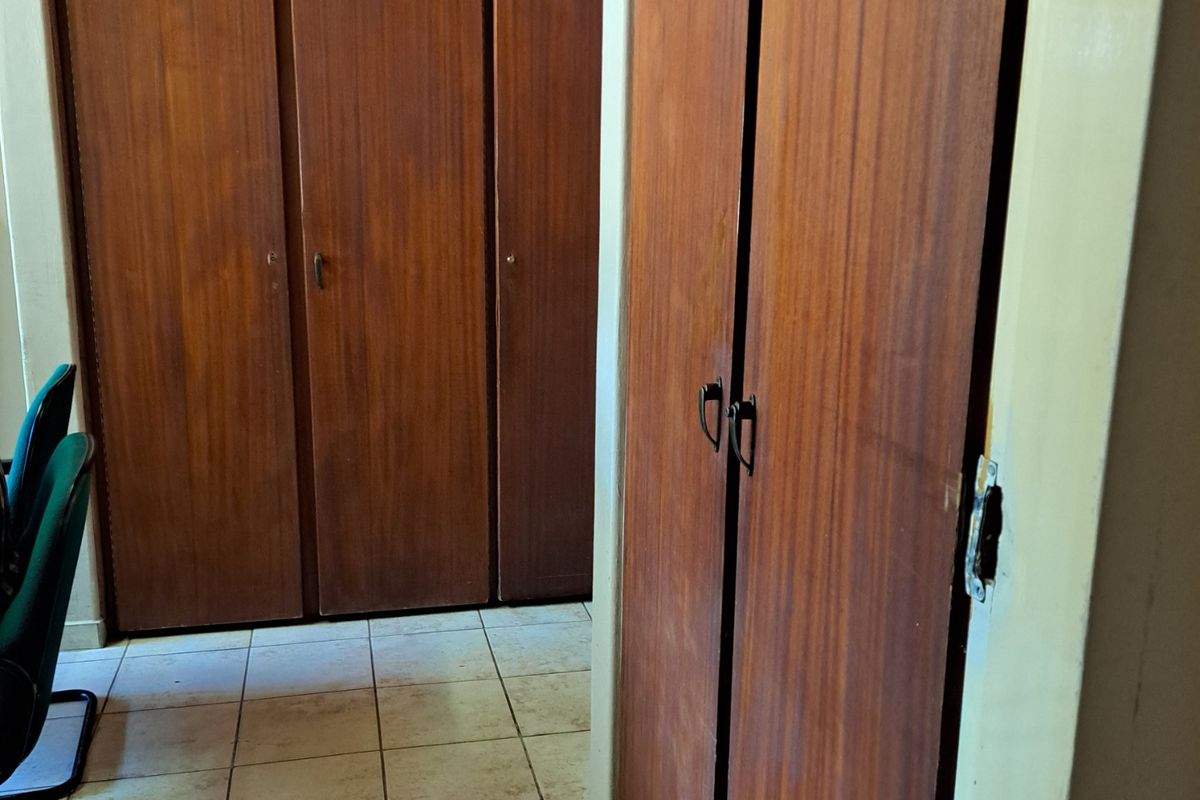 A bedroom featuring extensive built-in wooden cabinetry and tiled flooring, offering ample storage space.