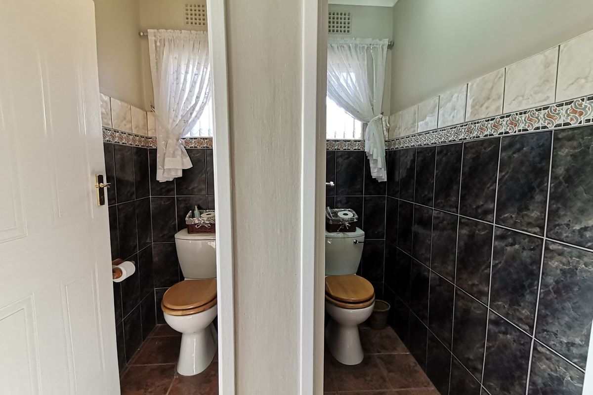 A dual-stall restroom facility featuring dark marble-effect wall tiling, ceramic floor tiles, and built-in toilet fixtures.