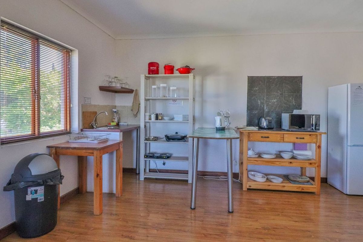 A basic kitchenette area featuring a sink, laminate flooring, and a window with blinds, currently lacking permanent built-in cabinetry.