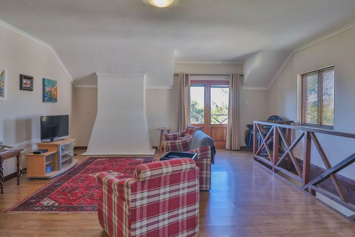 Spacious living room featuring a central fireplace, wooden flooring, and access to an outdoor balcony through double doors.