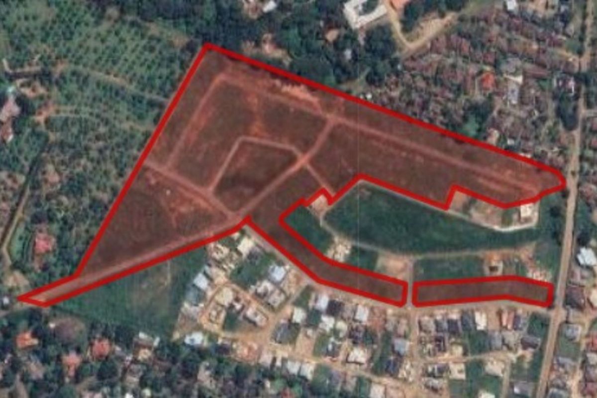 An aerial view of a large residential land parcel outlined in red, showing the site layout and surrounding neighborhood context.