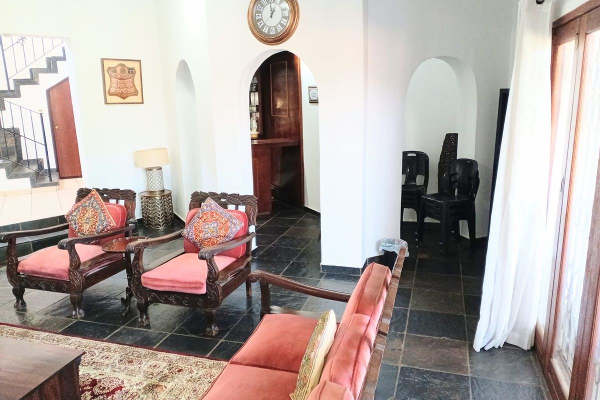 A living room featuring dark slate flooring, arched doorways leading to a bar area, and a staircase with wrought iron railings.