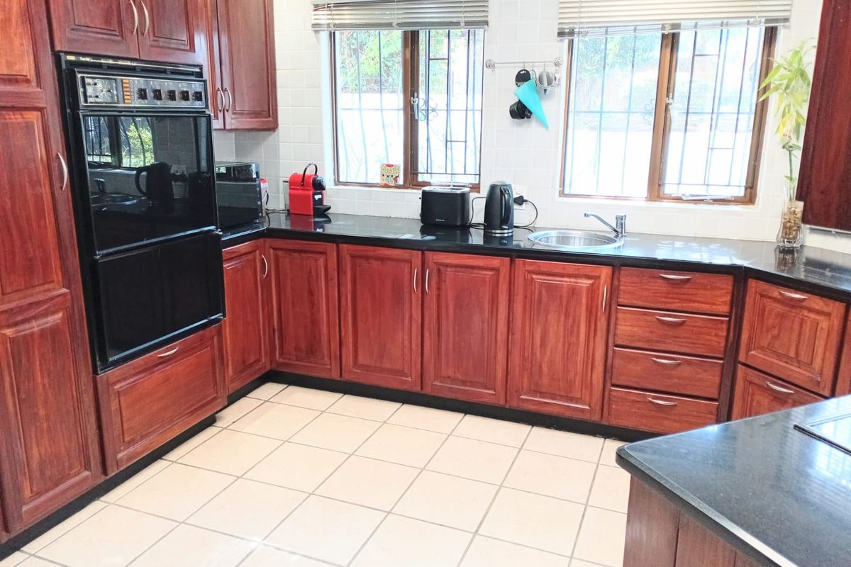 A functional kitchen featuring dark wood cabinetry, black granite countertops, tiled flooring, and a built-in eye-level oven.