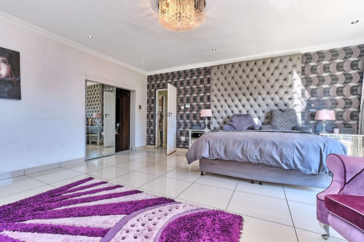 Spacious bedroom featuring large format floor tiles, recessed downlighting, decorative crown molding, and a built-in mirrored wardrobe.